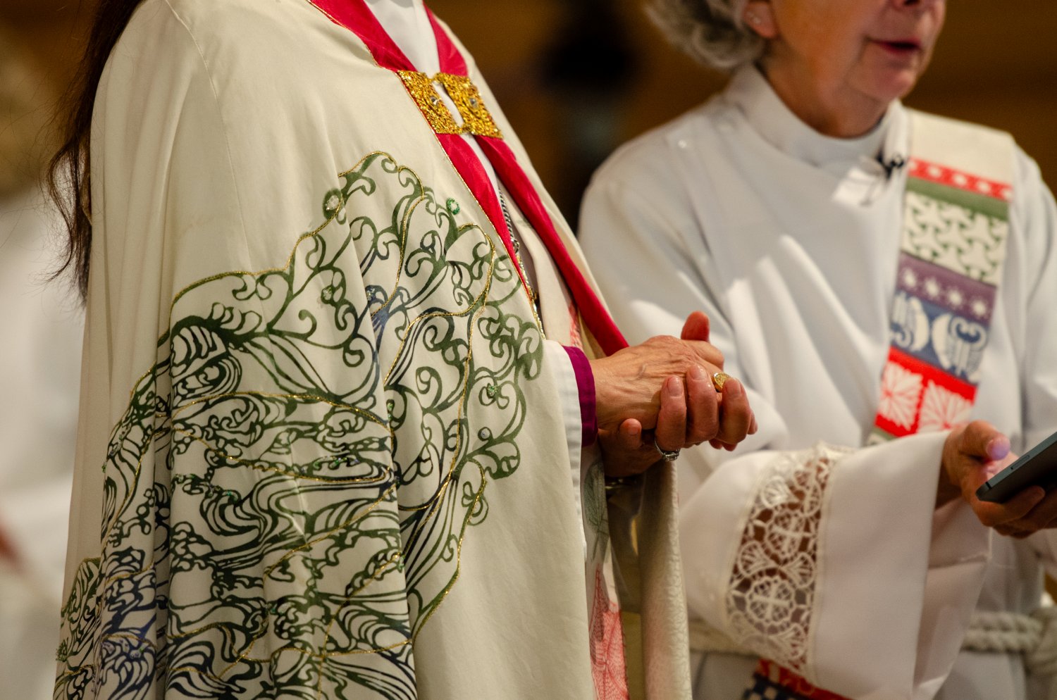 The folded hands of the bishop with detail of her beautifully embroidered robe