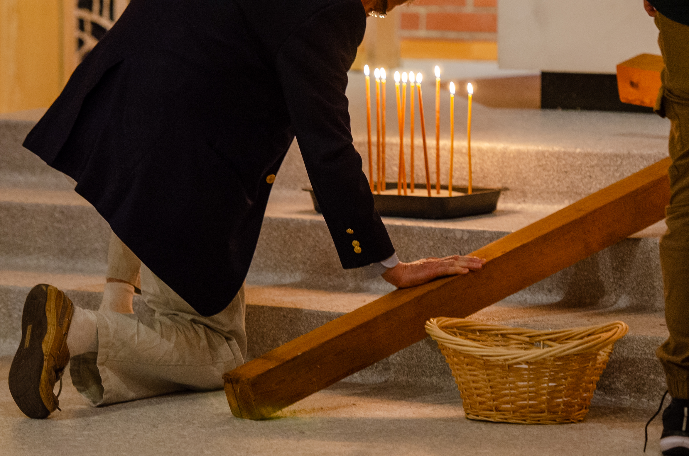 Man kneeling beside cross and candles