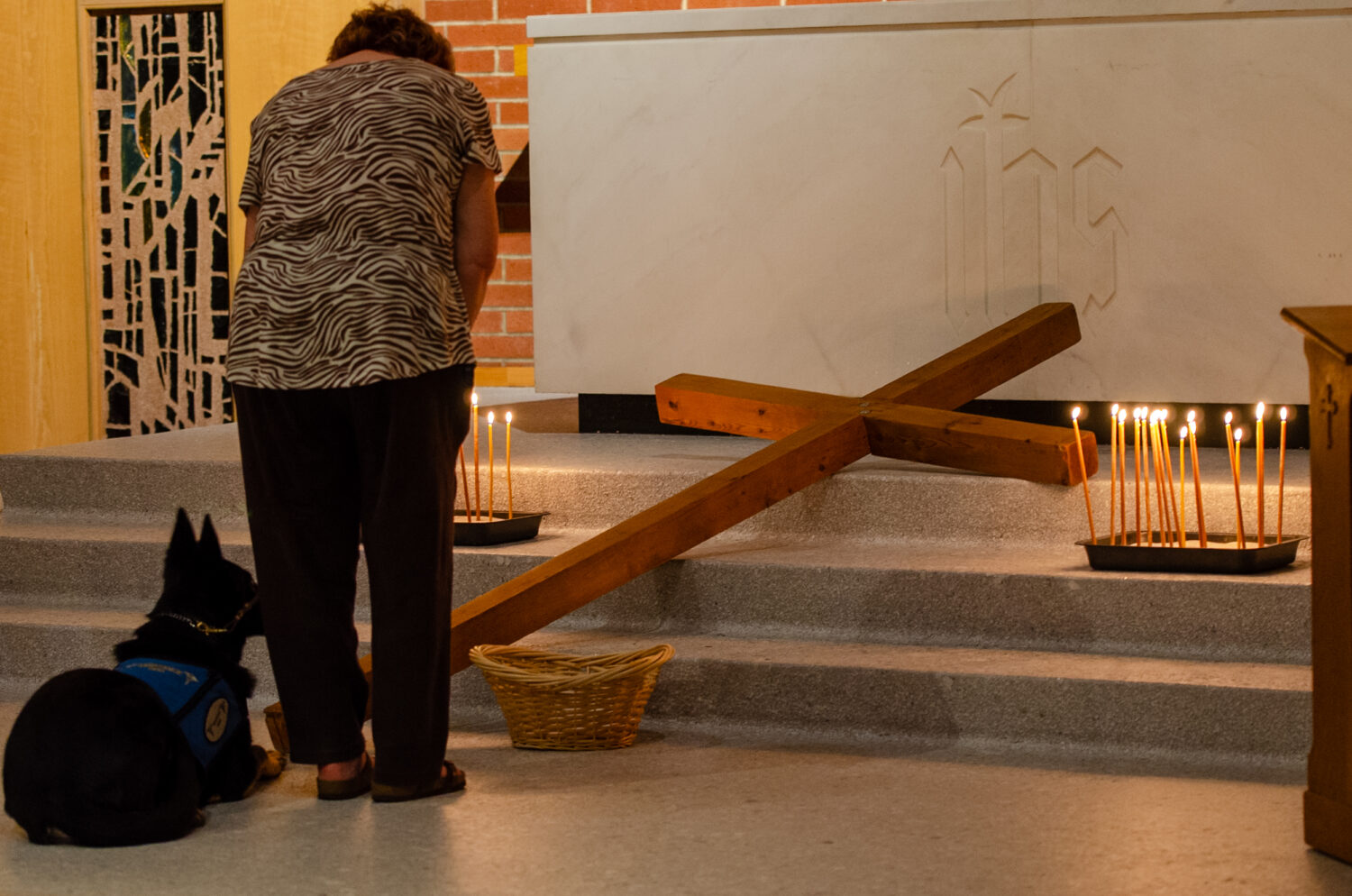 Woman prays at the cross with service dog