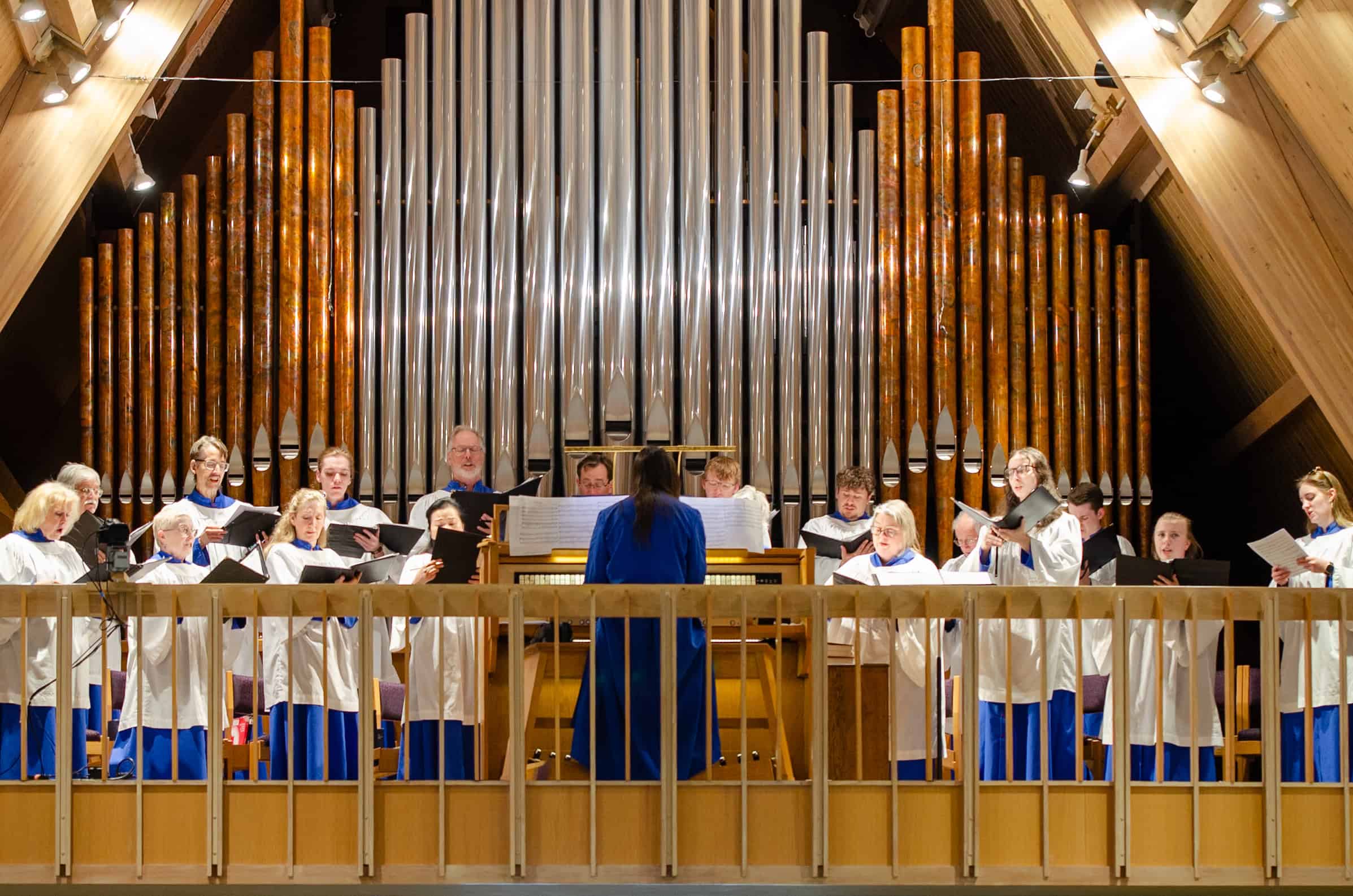 Church choir performing on stage with large pipe organ in the background.