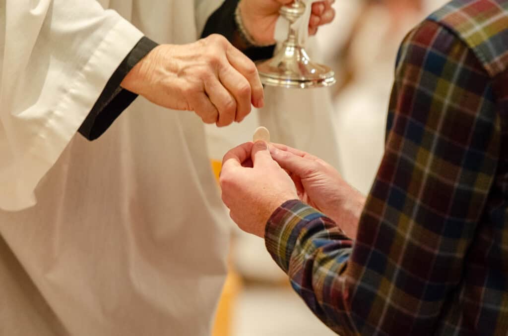 Clergy administering communion to a parishioner during church service.