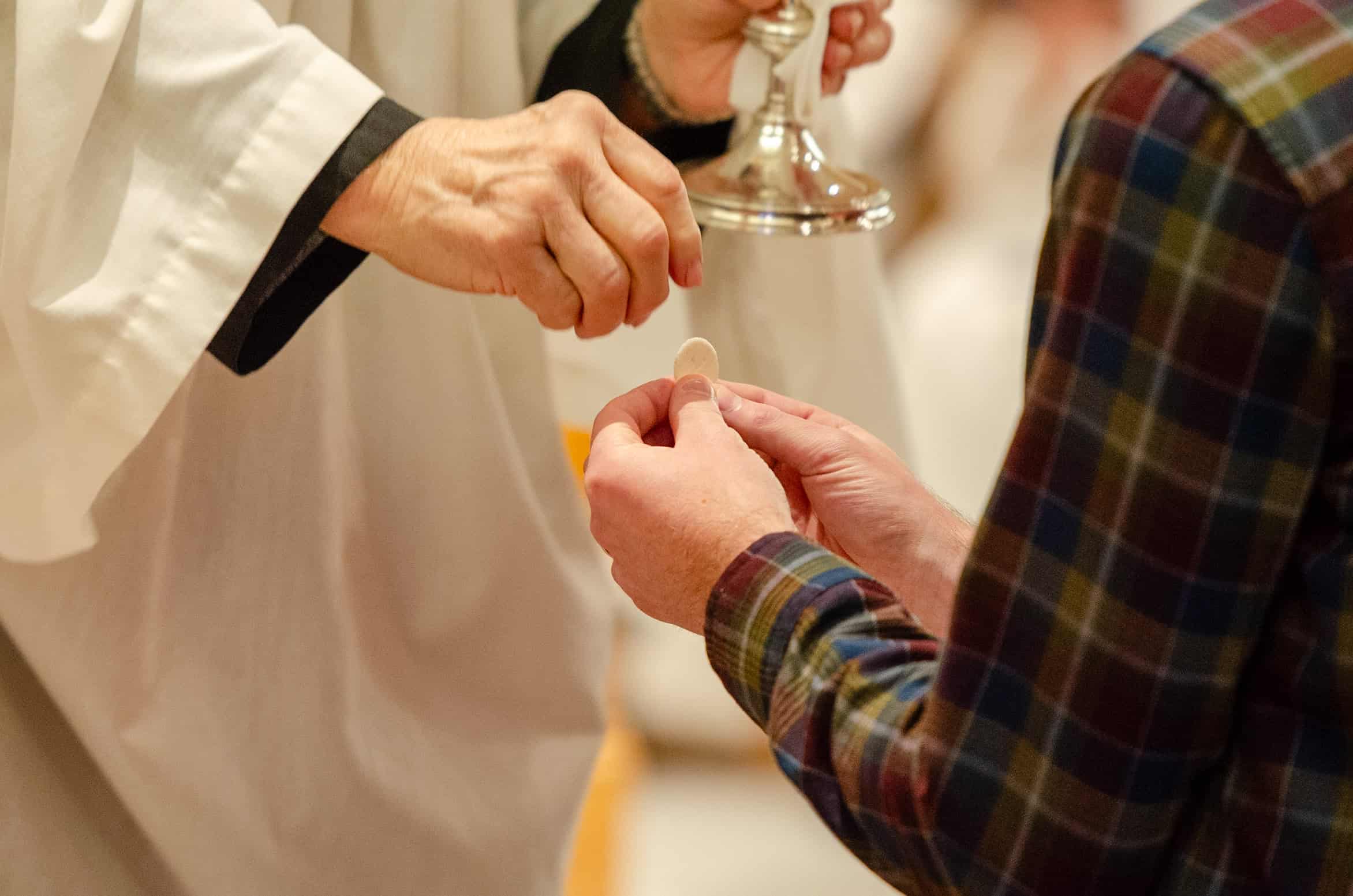 Clergy administering communion to a parishioner during church service.