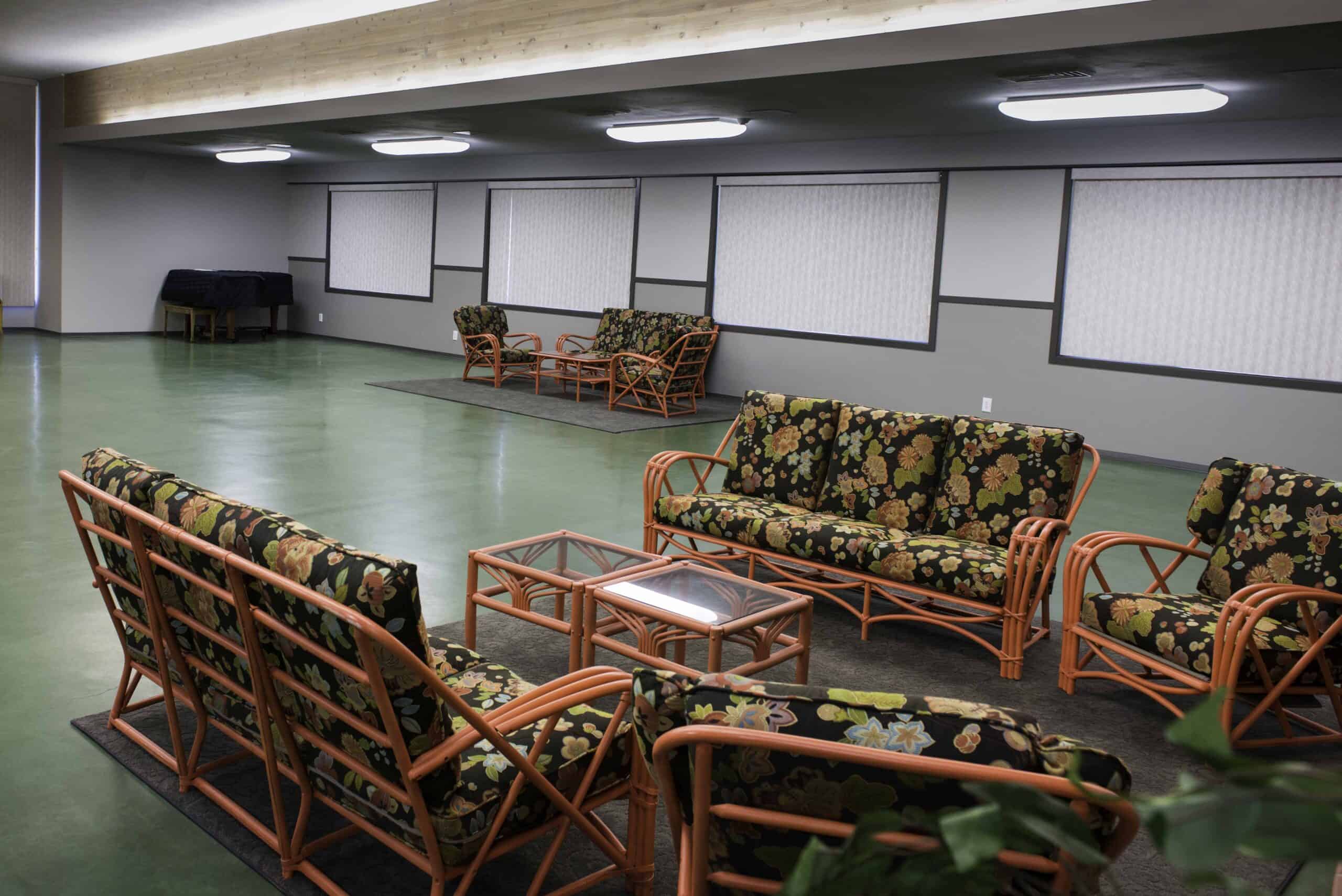 Interior seating area with floral-patterned furniture and large projection screens.