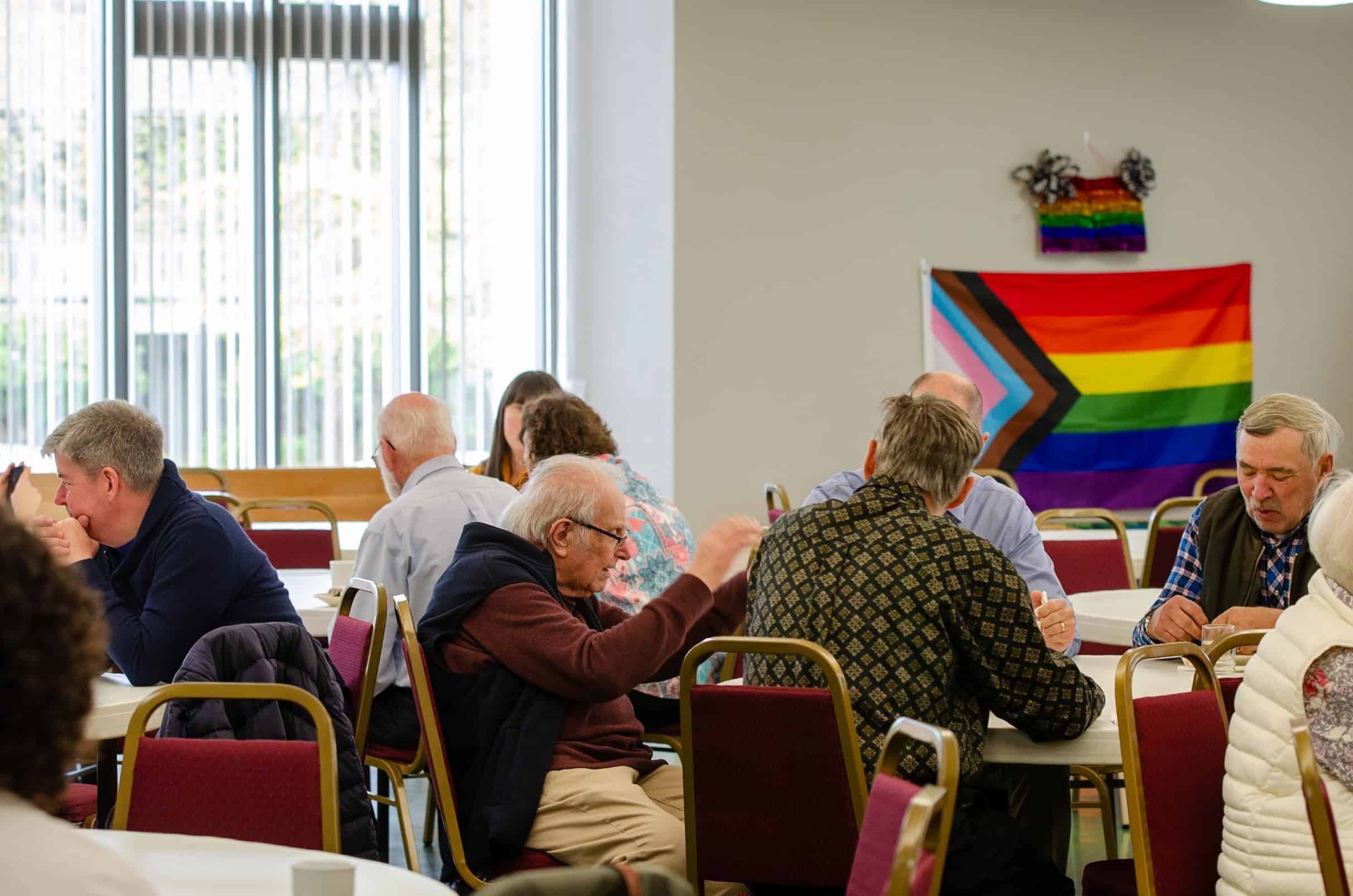 Community gathering at The Episcopal Church of the Good Samaritan with LGBTQ+ pride flag.