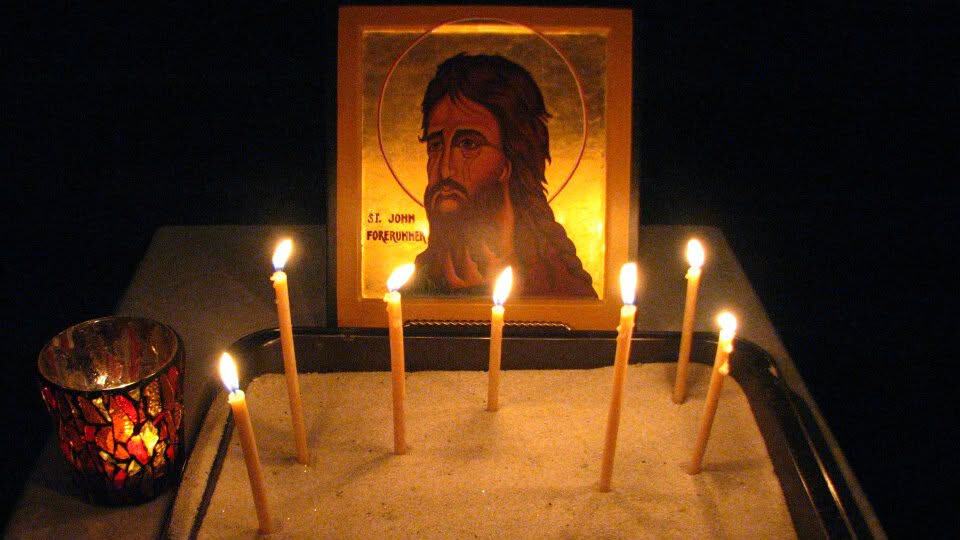 Religious icon of Jesus Christ with candles at prayer altar.